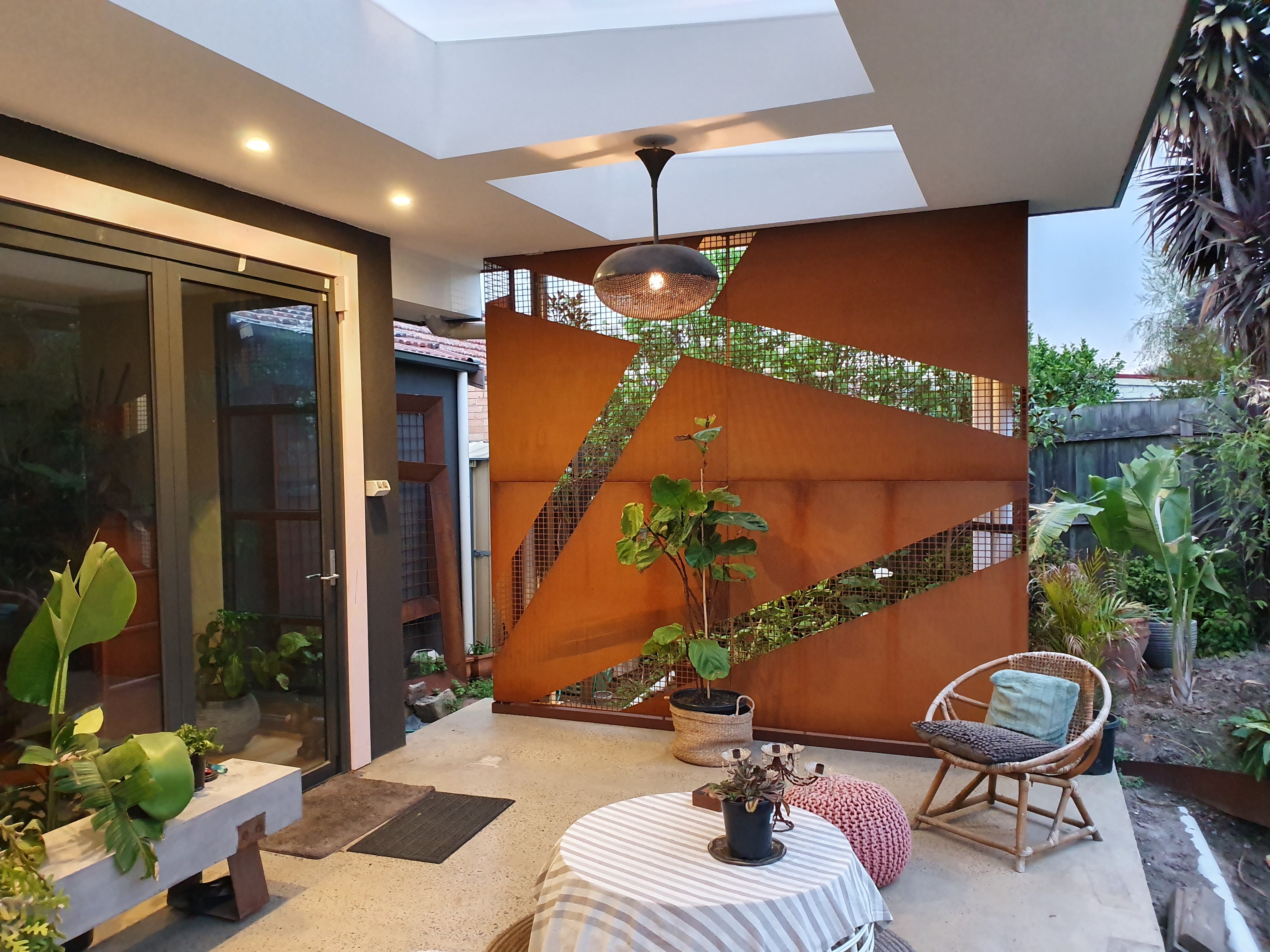  "Alt text: Alfresco screen featuring a bold corten cross pattern, created through laser-cutting of tiny squares. The screen is positioned to screen the end of the deck on the pagoda, adding a decorative element to the outdoor space."